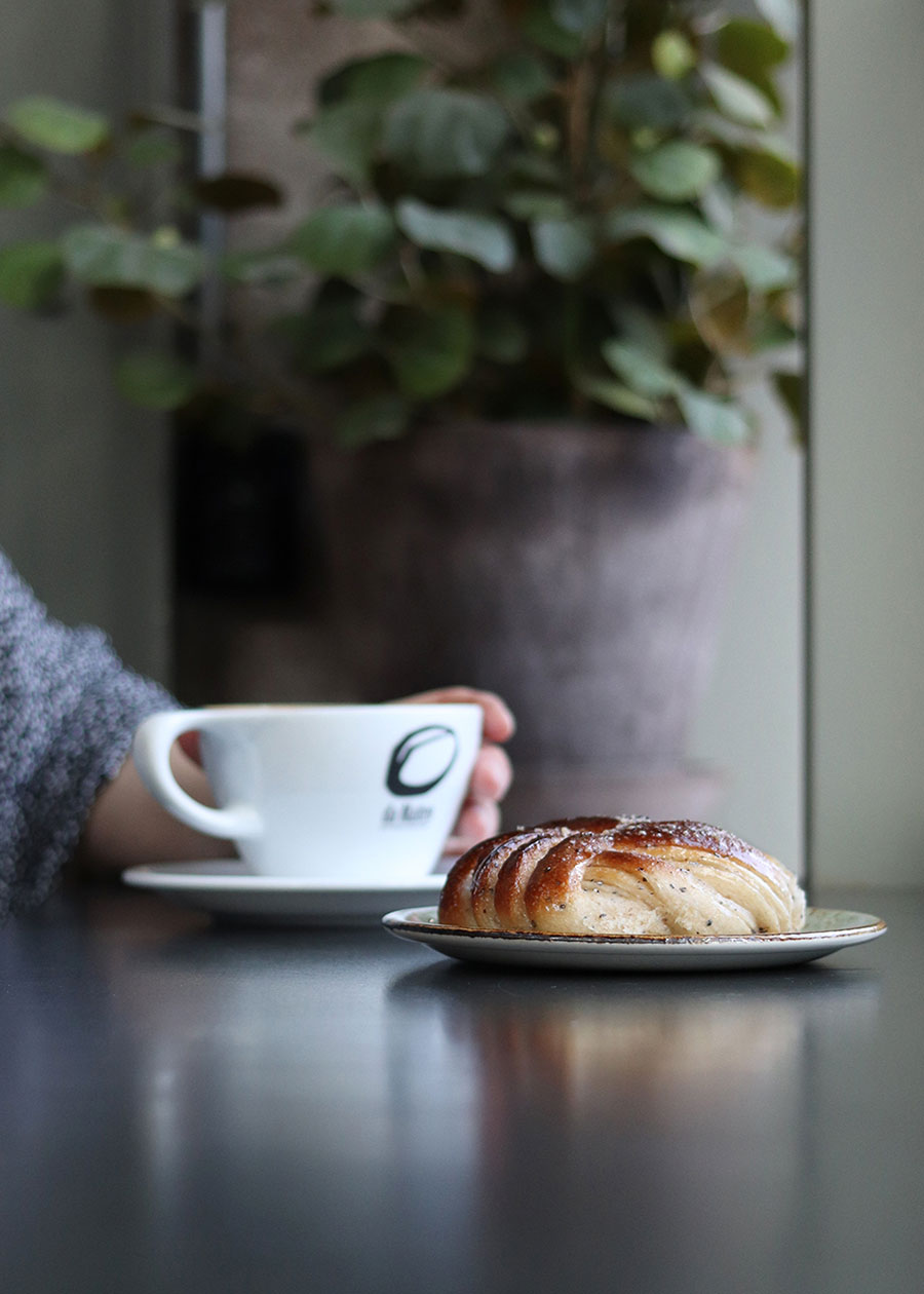 Eine Cafeszene mit Kaffeetasse und Zimtschnecke