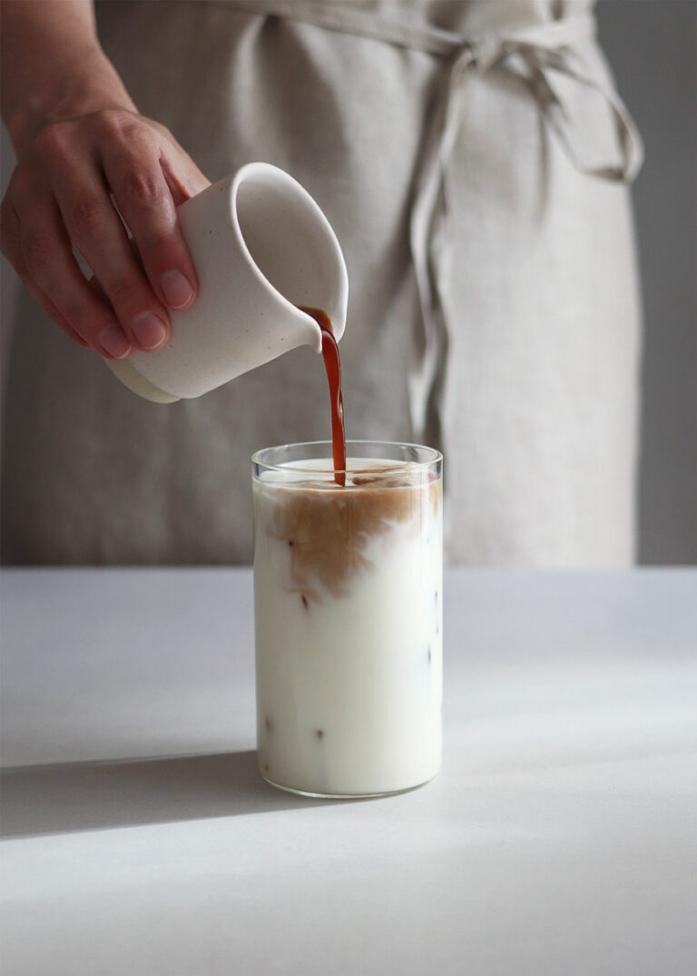 Foto Iced Latte - Eine Hand gießt Espresso in Milch