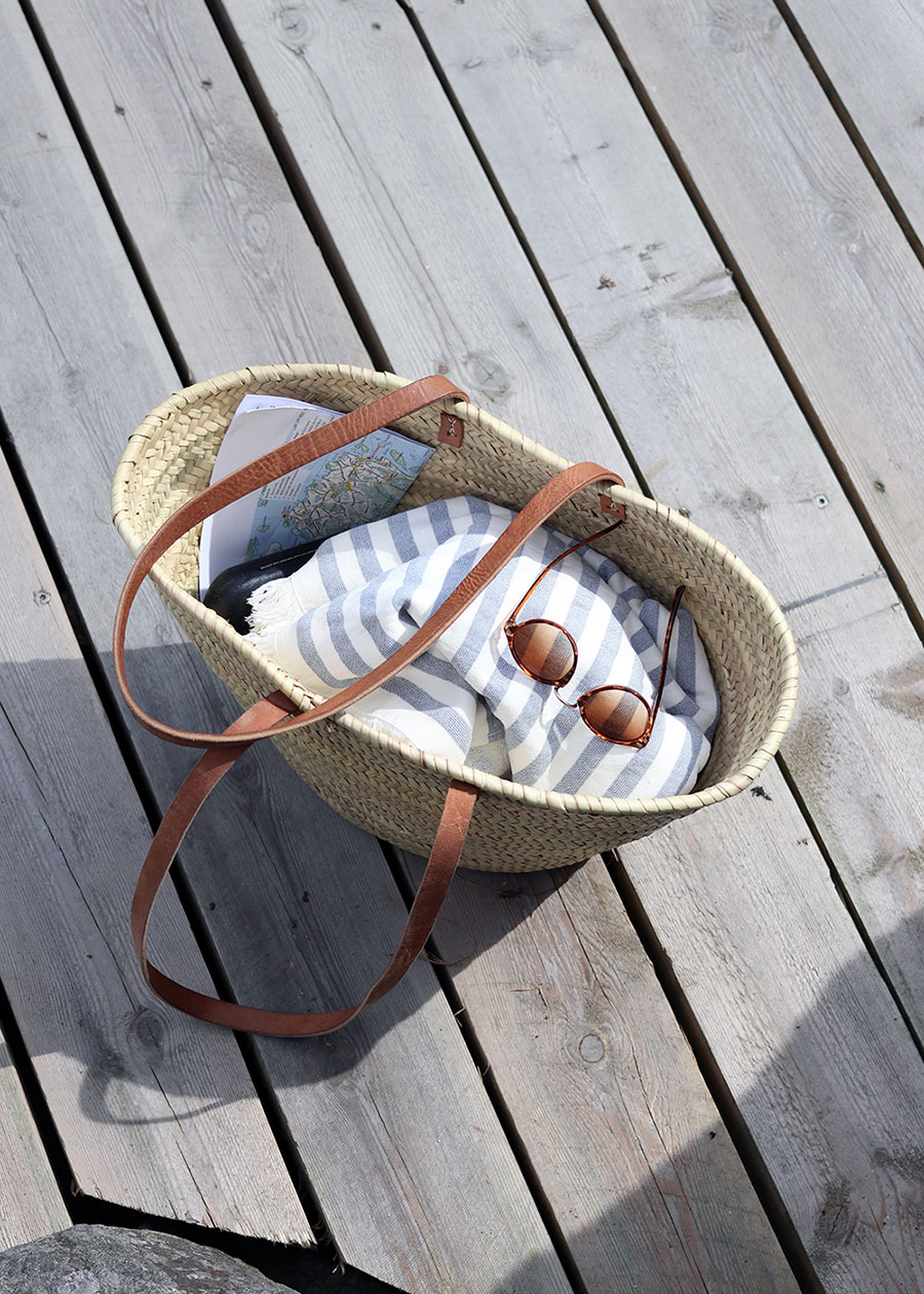 Eine Strandtasche mit Badetuch und Sonnenbrille