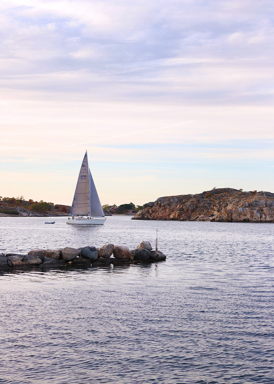 Abendstimmung am Wasser mit einem vorbeiziehenden Segelboot