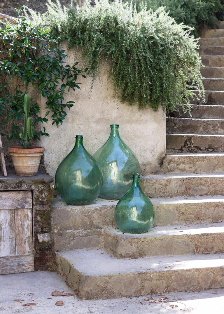 Große, grüne Glasvasen stehen als Dekoration auf einer Steintreppe